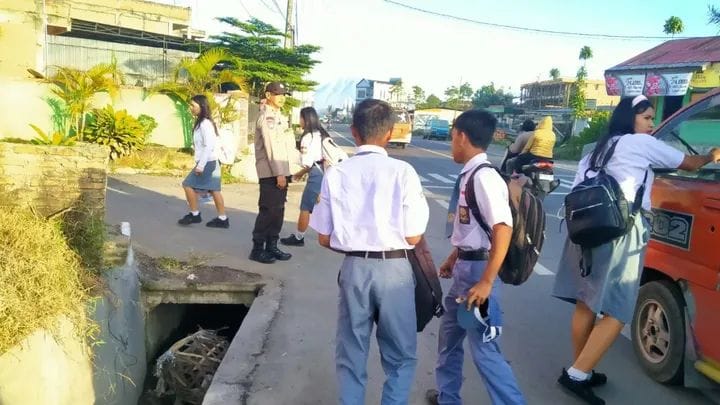 Foto :    Personel Polsek Tigapanah terlihat dengan tekunnya nya menyeberangkan siswa untuk kenyamanan para siswa, saat hendak menyeberang menuju sekolahnya.