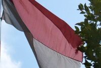 Bendera merah putih berkibar kusam dan koyak. 