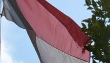 Bendera merah putih berkibar kusam dan koyak. 