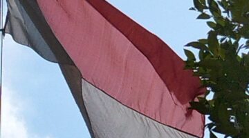 Bendera merah putih berkibar kusam dan koyak. 
